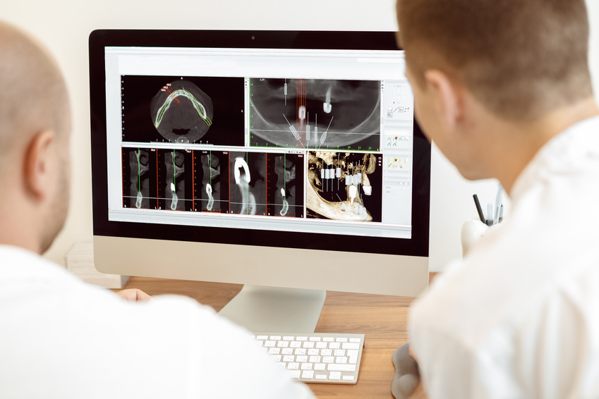 Dentists and assistant discussing the x-ray photograph on computer